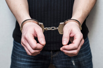 Man detained in handcuffs. Prisoner or arrested man in handcuffs. Male hands in handcuffs. Criminal law