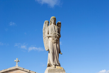An old beautiful melancholic and delicate sculpture statue at the llucmajor cemetery in mallorca island balearic spain on a sunny clear day 