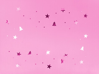 Confetti stars and trees sparkling on pink background.