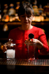 clean glass stands on bar and woman bartender pours wine from jigger into it