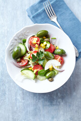 Healthy Salad with Green Olives, Baby Spinach, Cucumber, Cherry Tomatoes and Capers. Bright wooden background. Top view. Close up. 