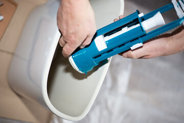A plumber installs a water pump in a ceramic toilet cistern. Drain system assembly, home repair