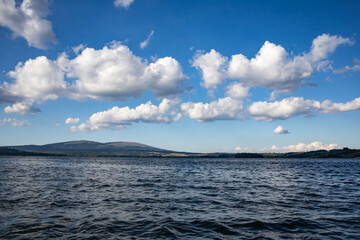 Obraz premium View from a boat of Vlasina lake with clouds on the blue sky