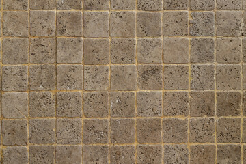Mosaic texture made of natural sandstone. Closeup on a small square stone pavement background.