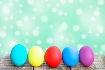 colorful easter eggs on wooden table on green background with bokeh. copy space