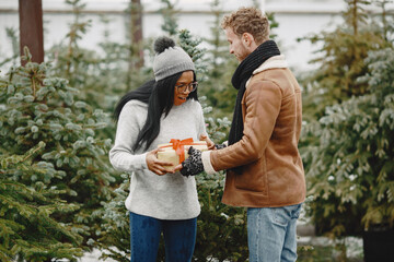 Winter concept. Guy in a brown coat. Salesman of Christmas Tree. International couple.