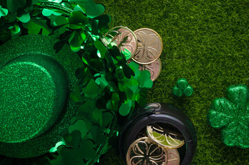 Composition for St. Patrick's Day with shiny hat of leprechaun with clover and coins on green grass...