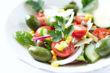 Healthy Salad with Green Olives, Baby Spinach, Cucumber, Cherry Tomatoes and Capers. Bright background. Close up.