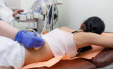 The doctor makes an examination of the young patient on the ultrasound machine lying on her stomach.