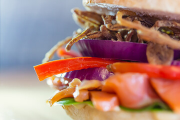 Closeup shot of one half of a Salmon gravlax sandwich with onion bringing out its taste, taken from...