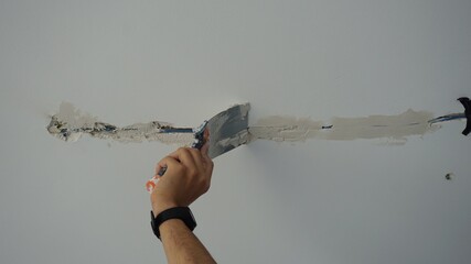 Mano tapando regata con yeso blanco 