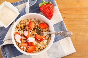 Bowl of cereals with strawberries resting on a blue napkin