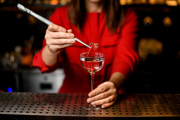 view of wineglass which woman decorates with branch of plant using tweezers