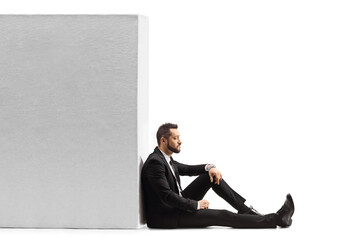 Pensive businessman sitting on the floor and leaning on a wall