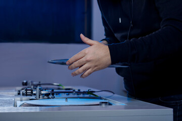 Dj colocando un disco de vinilo en su tocadiscos mientras mezcla música en una tienda de discos. Concepto de música retro