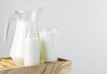 A jug and bottle of fresh milk glass on a wooden crate box. Raw milk is high in calcium and protein to drink for all ages. Milk consumption nutritious and healthy dairy products concept.