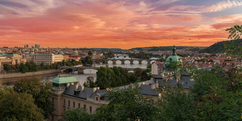 Fototapeta na wymiar .panorama of the city of Prague in the spring and bridges on the Vltava river between them and the Charles Bridge and the roofs of buildings during the day orange sky 