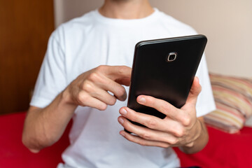Unrecognizable person using a tablet at his bedroom. Close up shot.