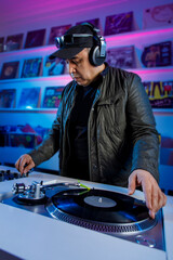 Hombre Dj mezclando música en un tornamesa con discos de vinil, y escuchando en los audífonos....