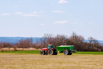 Tractor spreading fertilizer on grass field. Agricultural work.