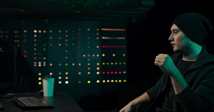 A nervous hacker with dark circles under his eyes hits the table with nerves after a failed attack on corporate data servers. He works on a computer in a secret hideout.