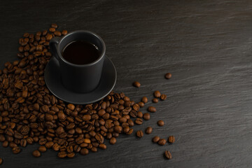 Hot coffee cup and coffee beans on black background top view