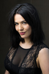 Fototapeta premium Portrait of a young sexy brunette girl in a lace top in dramatic tones. Vintage photo.