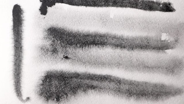 brush strokes of watercolor black paint with stains on a sheet of white paper.