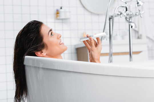 cheerful woman talking on mobile phone while taking bath - Powered by Adobe
