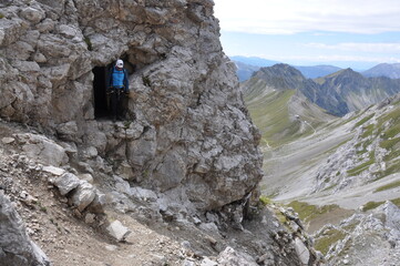 Człowiek w białym kasku stoi w skalnym otworze, Dolomity, Włochy