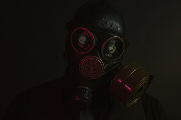 cosplay of a guy in a gas mask with a red light on a dark background with glowing eyes