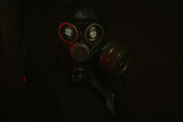 cosplay of a guy in a gas mask with a red light on a dark background with glowing eyes