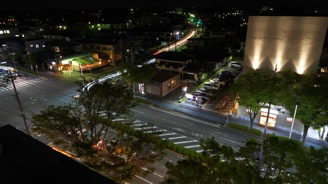 Long bright trails from headlights of moving cars, time lapse shot of night street at small town. Not many vehicles pass by street crossing at late hour