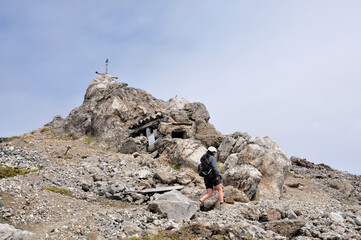 Człowiek podchodzi szlakiem na szczyt z krzyżem, Dolomity