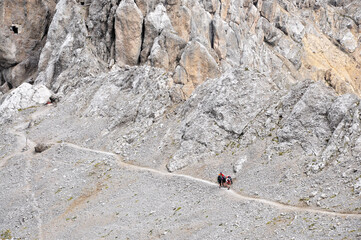 Fototapeta premium Ludzie idą ścieżką ponad stromym żlebem, Dolomity, Włochy