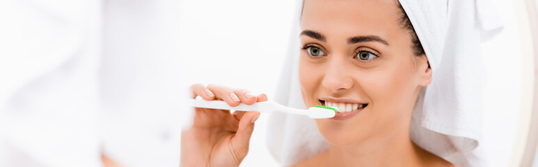 young woman with white towel on head brushing teeth in bathroom, banner