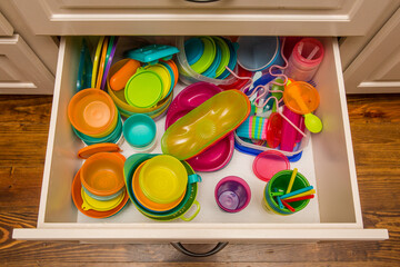 Kitchen drawer filled with colorful plastic storage containers and cups
