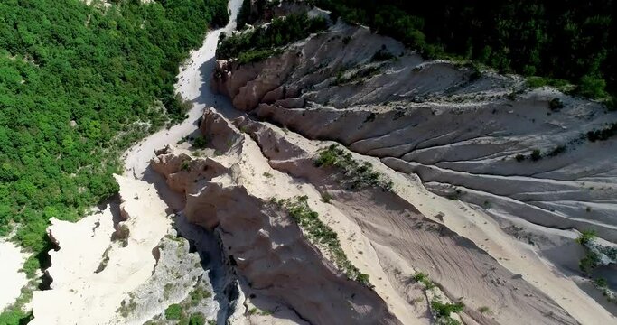 Aerial drone view of Lame Rosse Canyon, in Italy, trekking day in a suggestive place. Red earth columns and towers are formed by the erosion of water and wind. A geological phenomenon of great impact
