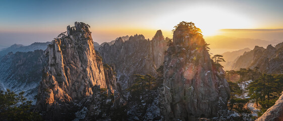 Panorama view of the mountain peaks of Huangshan National park, China. A lot of snow and clouds in the sunrise time with the winter season. Landscape of Mount Huangshan of the winter season.