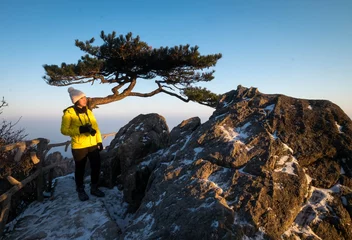 Photo sur Plexiglas Monts Huang The asian girl looking the scenry view and a lot of snow and pine tree of the mountain peaks at Huangshan mountain at the winter season , Anhui province China.