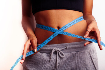 woman measuring waist with tape on knot, african tan isolated