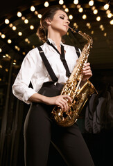 Fototapeta na wymiar Gorgeous brunette model woman in fashionable formal suit with saxophone