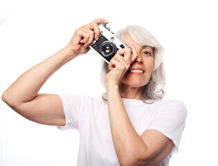 Lifestyle and people comcept: Happy elderly woman is holding a camera and smiling over white background