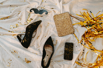 Celebrating New Years Eve. Glitter sparkling confetti. Cocktail party night. Having fun. Golden and white wall. Black high heels. Glitter purse. After party. Photo props. Happy Birthday. 