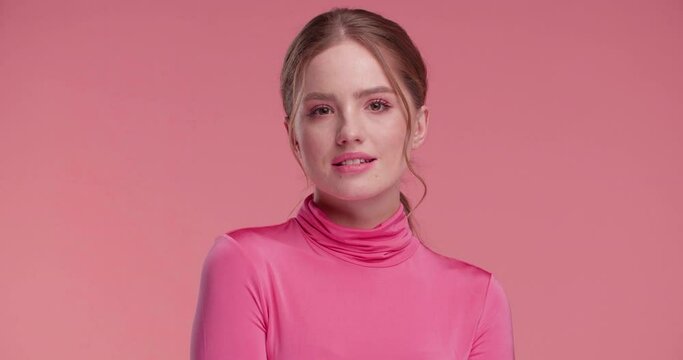  Girl in Pink Outfit  smiling charmingly and looking to the Camera standing in isolated Pink studio