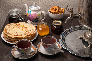 Tea party with samovar, crepes, bagels, honey, jam