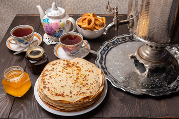 Tea party with samovar, crepes, bagels, honey, jam