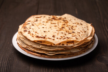 stack of pancakes on a plate on a dark wooden table
