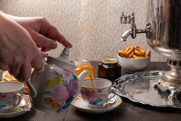 Pouring tea into a cup. A tea party with a samovar.