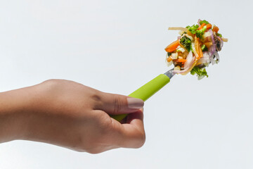 Mano de mujer sosteniendo una cuchara con ensalada de vegetales